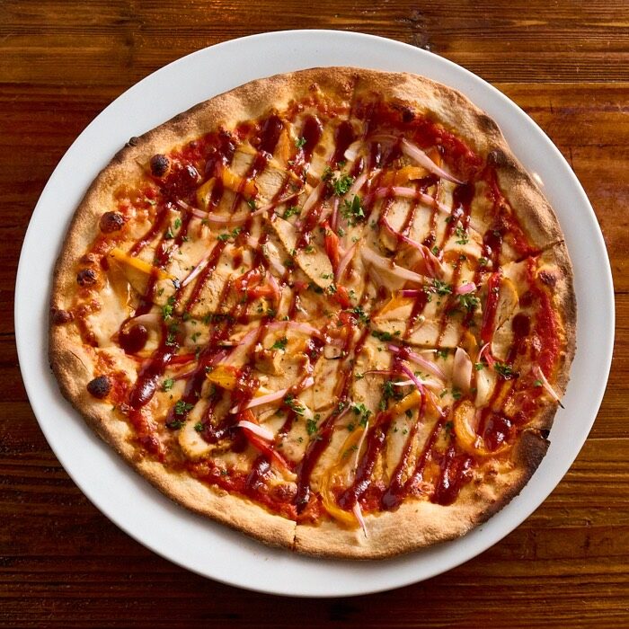 BBQ chicken pizza with roasted peppers, red onion and a barbecue sauce drizzle