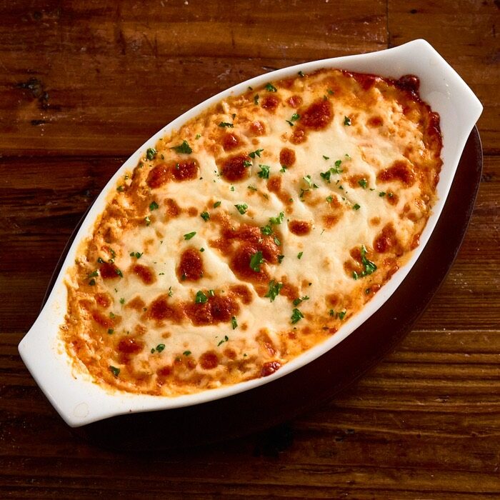 Baked buffalo chicken dip topped with melted cheese in an oval dish