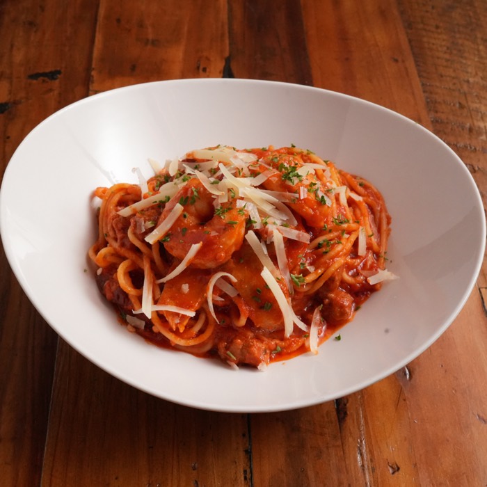 Cajun jambalaya pasta in chili tomato sauce with chicken and shaved parmesan