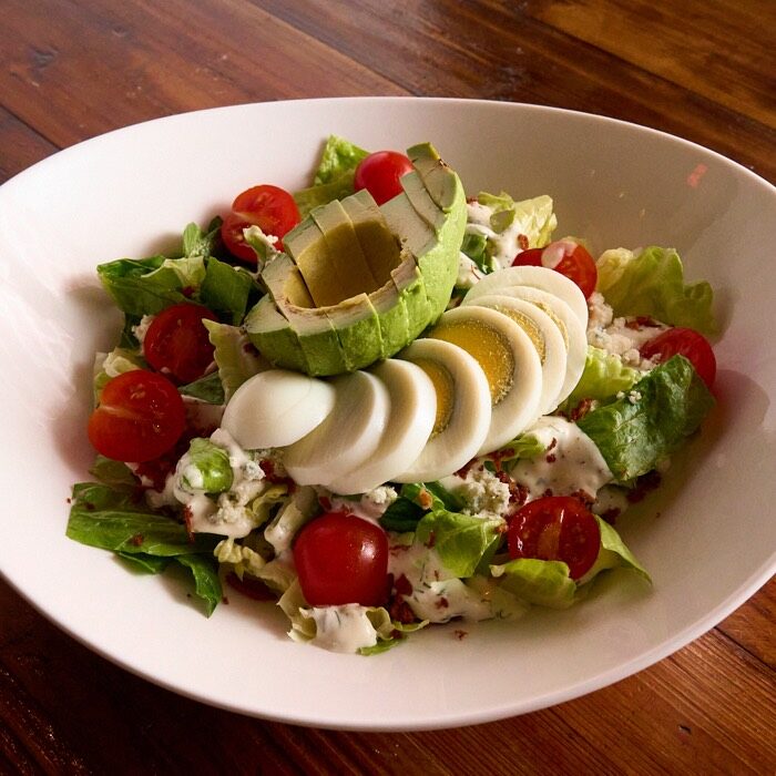 Classic cobb salad with romaine, cherry tomatoes, avocado, sliced egg, gorgonzola and bacon