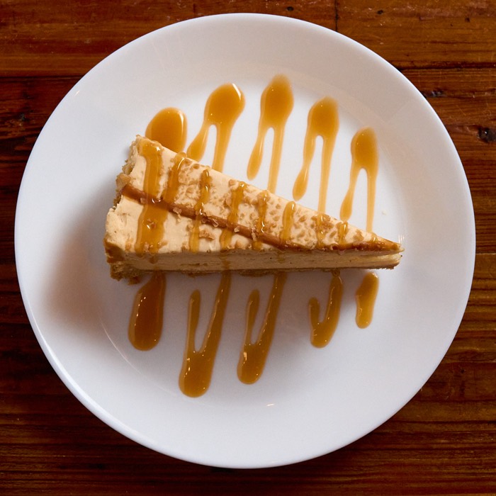 Slice of dulce de leche cheesecake with toffee crunch and caramel drizzle