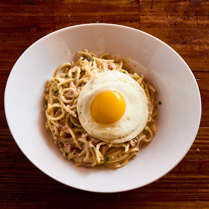 JZ's spaghetti carbonara topped with a sunny-side-up egg, bacon and parmesan