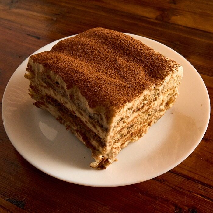 Slice of homemade tiramisu dusted with cocoa
