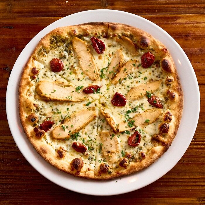 Tuscan chicken pizza with basil pesto, chicken breast and sun-dried tomatoes