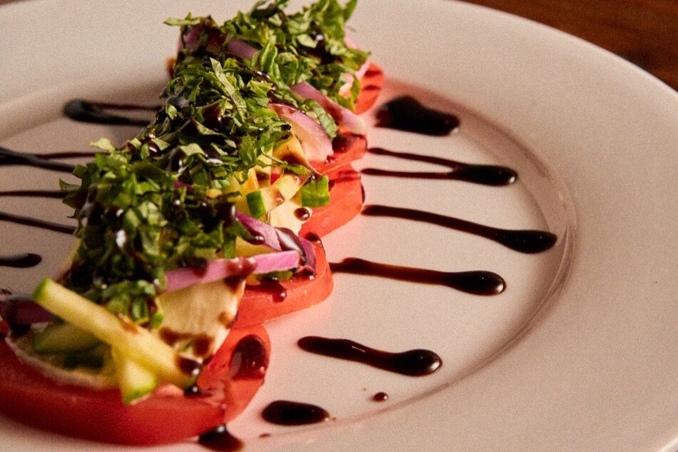 Caprese appetizer plated with balsamic glaze and micro greens